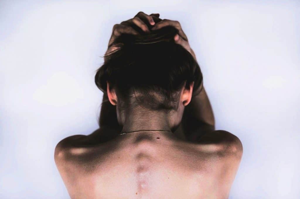 Woman with hands on head and spine bumps showing