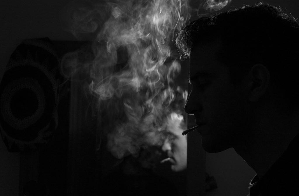 man smoking black and white